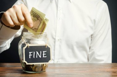 Bir adam içinde Fine yazan cam bir kavanoza dolar koyar. Para biriktirip para cezası ödüyorum. Bir suç ve suçun cezası. Finansal ceza. Trafik kurallarının ihlali. Sahtekar. Para cezası.