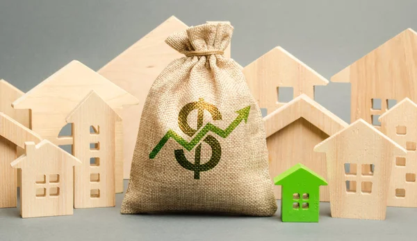 Sac d'argent avec flèche vers le haut et maisons en bois miniatures. Le concept de hausse des prix de l'immobilier. Taux hypothécaires élevés. Cher appartement à louer. Demande croissante pour l'achat d'une maison. Marché immobilier . — Photo