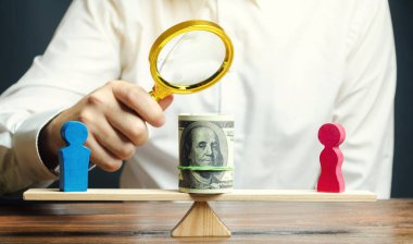 Terazide kadın ve erkek ahşap figürler. Cinsiyet ecret farkı kavramı. Gelir eşitsizliği. Kadınlara baskı. Cinsiyet ayrımcılığı. Kadın emeğinin hafife sayılma. Segregasyon.