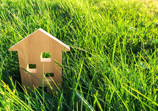 Miniature wooden house on green grass. Real estate concept. Modern housing. Eco-friendly and energy efficient house. Buying a home outside the city. Nature. Fresh air. Mortgage, loan.