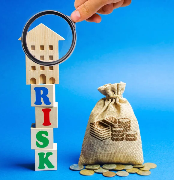 リスクという言葉で木製のブロックとお金の袋を持つミニチュアの家 不動産投資のリスク リスク投資だ 非支払いのためのプロパティの損失 住宅ローン税 詐欺的な仕組み — ストック写真