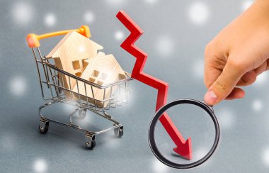 Süpermarket tramvayındaki minyatür ahşap evler ve aşağı ok. Düşük konut talebi kavramı. Kışın gayrimenkul indirimi. İpotek faiz oranları. Ucuz maliyet. Noel Kar Taneleri