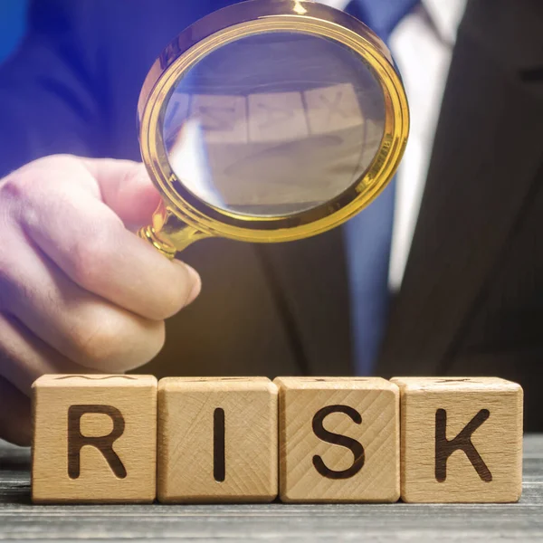 İş adamı Risk kelimesinin üzerinde büyüteç taşıyor. Finansal ve ticari risk kavramı. Risk değerlendirmesi ve yönetim. İş planı geliştirme. Planlama ve eylem stratejisi.