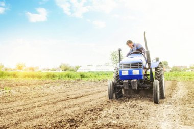 Farmer on a tractor with milling machine loosens, grinds and mixes soil. Loosening surface, cultivating the land for further planting. Farming and agriculture. Use of agricultural machinery on a farm. clipart