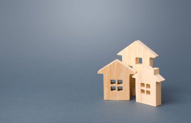 Gri arka planda ahşap evler. Satın alıp satma, kiralık konut. Apartman ve ev sahipleri. İnşaat endüstrisi, bakım ve kamu hizmetleri. İpotek kredisi emlak