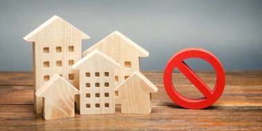 Wooden houses and a prohibition sign. Inaccessible and expensive housing. Restrictions and a ban on the construction of buildings. Interdictions within settlements. Inaccessibility Index clipart
