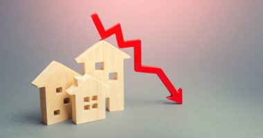 Minyatür ahşap evler ve bir kırmızı ok aşağıda. Düşük maliyetli gayrimenkul kavramı. Düşük ipotek faizleri. Kiralık konutların ve dairelerin fiyatları düşüyor. Ev satın alma talebi azalıyor