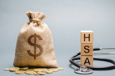 Wooden blocks with the word HSA and money bag with stethoscope. Health savings account. Health care. Health insurance. Investments. Tax-free medical expenses. Coins and dollar sign clipart