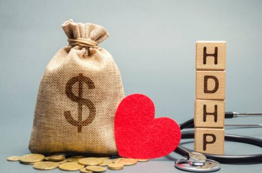 Üzerinde HDHP yazan tahta bloklar ve dolar işareti olan para çantası. Yüksek vergiden düşülebilir sağlık planı konsepti. Sağlık sigortası planı geleneksel sağlık planından daha düşük primlerle ve indirimlerle
