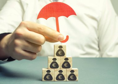 Sigorta şirketi, avronun görüntüsüyle tahta blokları koruyor. Tasarruf koruması. Parayı güvende tutmak. Yatırım ve sermaye sigortası. İş yapma riski. Yolsuzluk kayıpları.