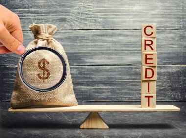 Para çantası ve terazide kredi yazan tahta bloklar. Başarılı bir kredi konsepti. Düzeltme ve kredi geçmişi oluşumu. Kredileri geri alıyorum. Uygun faiz oranları.