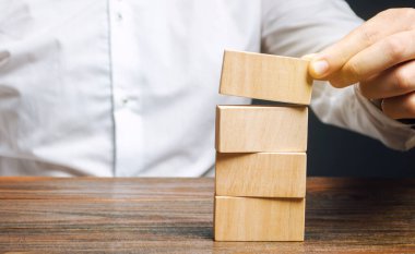 İşadamı tahta bloklar koyar. İş yönetimi konsepti. Planlama ve strateji. Ayarlama ve hedeflere ulaşma. İş dengesi. Yol haritası.