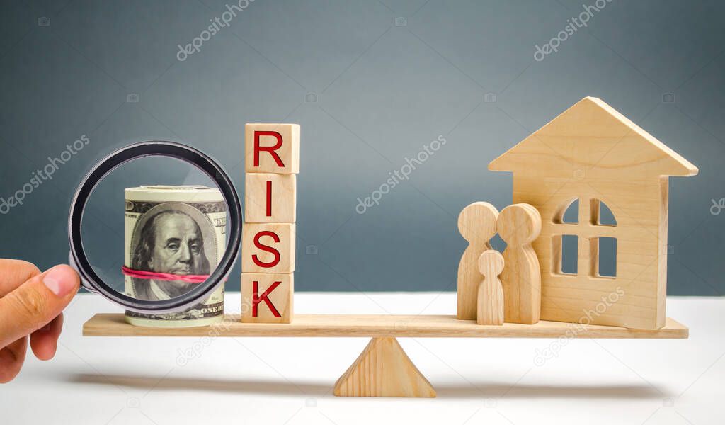 Wooden house and cubes with the word risk and family stand on scales. The concept of risk, loss of real estate. Property insurance. Loans secured by home, apartment. Financial risks, litigation.
