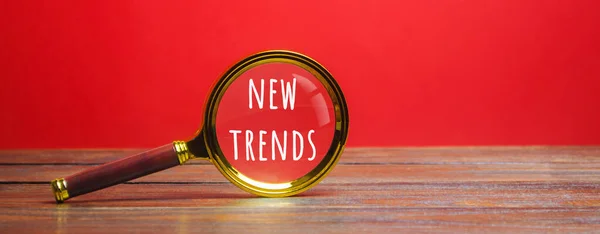 Magnifying glass with the inscription New Trends. The concept of searching for new ideological trends and tendencies. Exclusive trend. Popular and relevant topics.