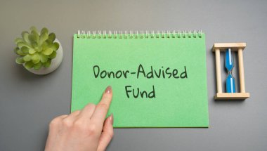 Bağış Danışmanı Fonu konsepti. Bireylerin hayır kurumlarına bağış yapmalarına ve derhal vergi yardımı almalarına olanak sağlayan bir yardım aracı. İş ve finans. Üzerinde yazı olan not defterine bakan kadın