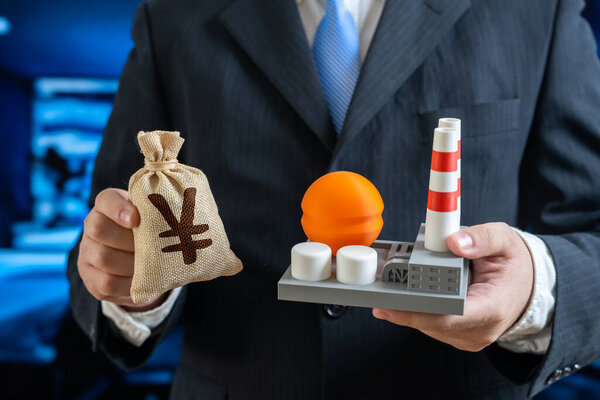 Yen or yuan money bag and chemical plant in the hands of a businessman. Investments in the energy or chemical sector. Symbol of petrochemicals, trade, finance, taxes, and economy.