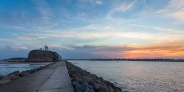 Sunset at Nobbys Breakwall with lighthouse and Hunter river. Newcastle is a harbour side city in New South Wales Australia. clipart