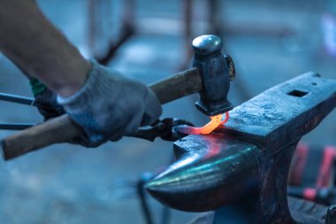 Smith iş arkasında. O ısıtılan metal parçası tutan smith kerpetenler, ellerinde. Örs üzerinde smith eğilerek ayrıntı düşündüm bir metal uydurandan. Sıcaklık Metal kırmızı