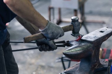 Smith iş arkasında. O ısıtılan metal parçası tutan smith kerpetenler, ellerinde. Örs üzerinde smith eğilerek ayrıntı düşündüm bir metal uydurandan. Sıcaklık Metal kırmızı