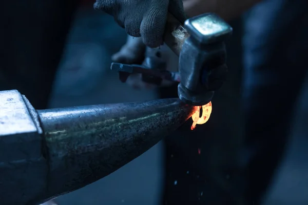 作品の背後にスミス スミス ニッパーで手では 暖められた金属片を保持します 詳細を考え出した金属を偽造スミス アンビルに傾いています 温度から金属赤 — ストック写真