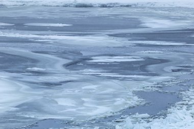 Şiddetli kış aylarında nehir üzerinde donmuş yüzey. Kalın buz kardan bakar. Kıyıda buz kütlelerinin keskin kıymıkları