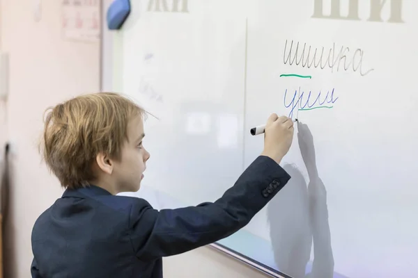 Okulda bir yönetim kurulu, beyaz çocuk. Çocuk bir kelime bir gemide yazıyor ve onları hecelere ayırır