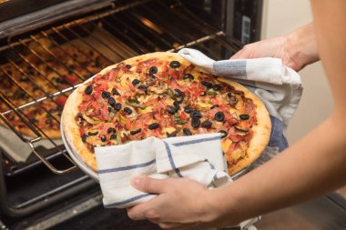 Genç kız hazır pizza bir fırından alır.