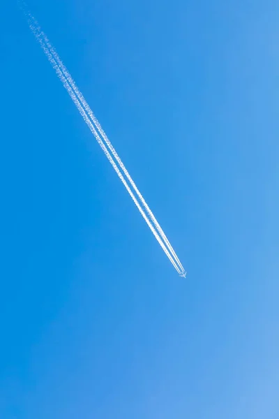 El avión vuela alto en el cielo azul, reservando un rastro blanco — Foto de Stock