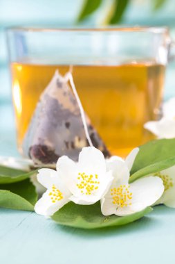 Mavi bir arka plan üzerinde sıcak yasemin çayı ile Cam fincan. Çay poşeti