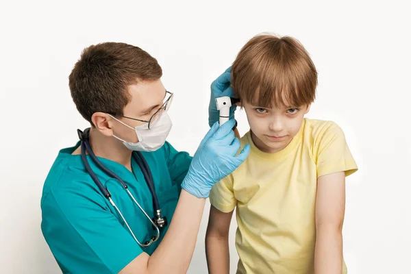 Pediyatrist, klinikte othcope ile çocukların kulaklarını inceliyor.