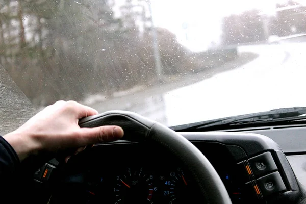 the driver rides behind the wheel of the car in rainy weather