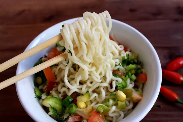 Bir tabakta yemek çubukları ile terbiyeli şehriye