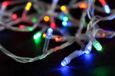 siyah arka plan üzerinde renkli Noel çelenk parıldıyor