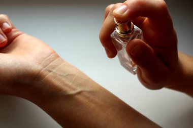 Women`s hands squirting perfume on her wrist clipart