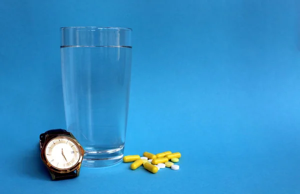 Blå Bakgrund Klocka Ett Glas Vatten Och Medicin — Stockfoto