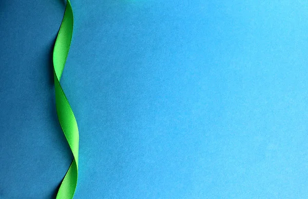 Nastro Raso Verde Contorce Sfondo Blu — Foto Stock