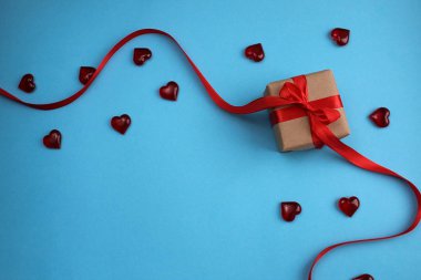 Mavi bir arka plan üzerinde kırmızı bir yay ile sarılmış hediye