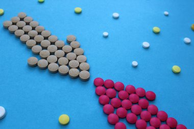 Pembe ve gri mavi bir arka plan üzerinde bir ok şeklinde haplar