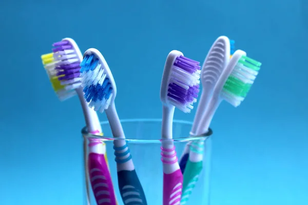 Beş Diş Fırçası Mavi Bir Arka Plan Üzerinde Bir Cam — Stok fotoğraf