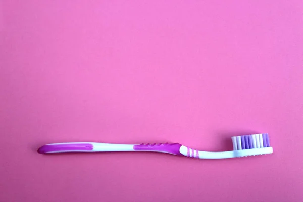 Bir Diş Fırçası Pembe Bir Arka Plan Üzerinde Yatıyor — Stok fotoğraf