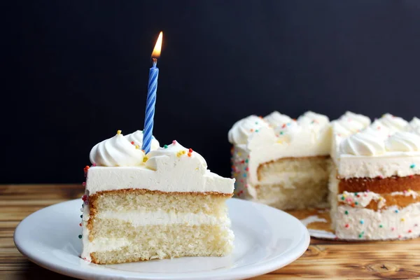 beyaz krema ve yanan tek bir mum ile pasta bir parça