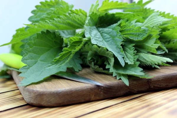 A bouquet of nettles lies on a wooden table with a knife — Stock Image Bouquet Nettles Lies Wooden Table Knife Stock Picture