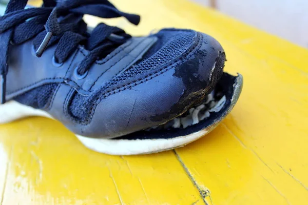 Torn blue shoe on a yellow background