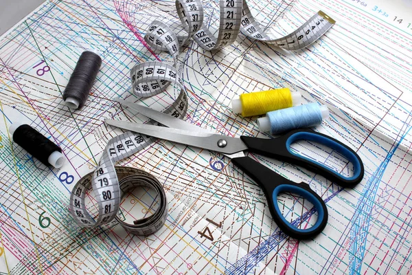 On sewing patterns are scissors, thread and tape measure