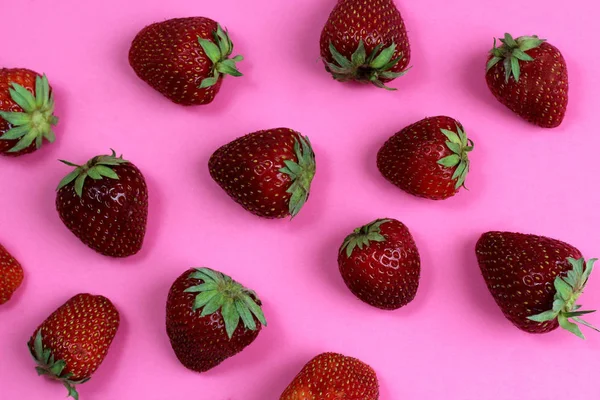 Texture strawberry on a pink background. Ripe fresh strawberry berries close-up. View from above