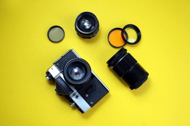 Retro kamera. Eski film kamera ve lensler sarı bir arka plan üzerinde yatıyor