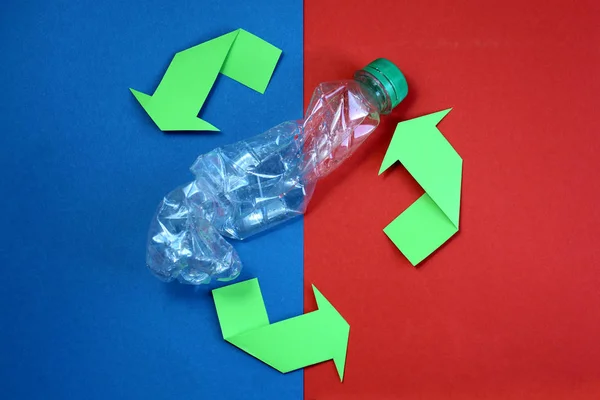 Green arrows recycle it symbol on a blue and red background. recycled material symbol. Used crumpled bottle.