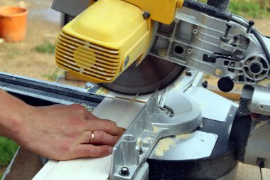 Açık havada iş başında marangoz elektrikli testere ile ahşap bir tahta testere