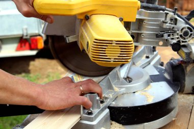 Açık havada iş başında marangoz elektrikli testere ile ahşap bir tahta testere