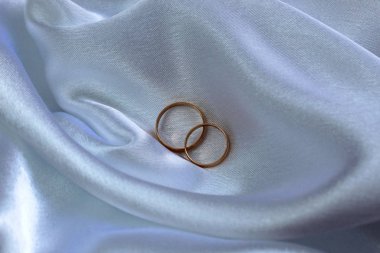 Altın alyanslar saten kumaşın üzerinde.